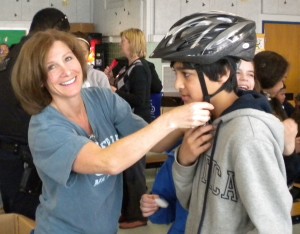 Melissa Landau fitting a Herndon Elementary School student with a new bike helmet as part of the ABRAMS LANDAU "putting lids on the kids" head safety and brain injury prevention program