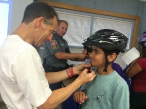 It takes lots of "hands on" helpers to properly fit each student with their FREE bicycle helmet at the ABRAMS LANDAU & Virginia Trial Foundation's brain injury prevention programs