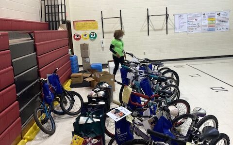 a dozen bicycles with bags of donated food, in gymnasium at Potowmack Elementary School.