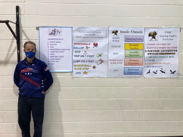 Attorney Doug Landau posing next to fitness posters in the Potowmack Elementary School gym in Sterling, VA