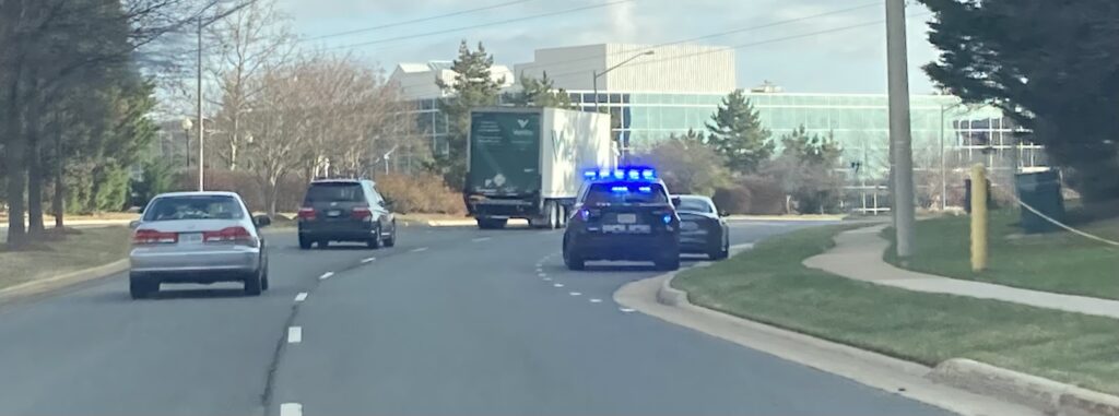 Cars and truck on suburban street, police cruiser with pulled over vehicle.