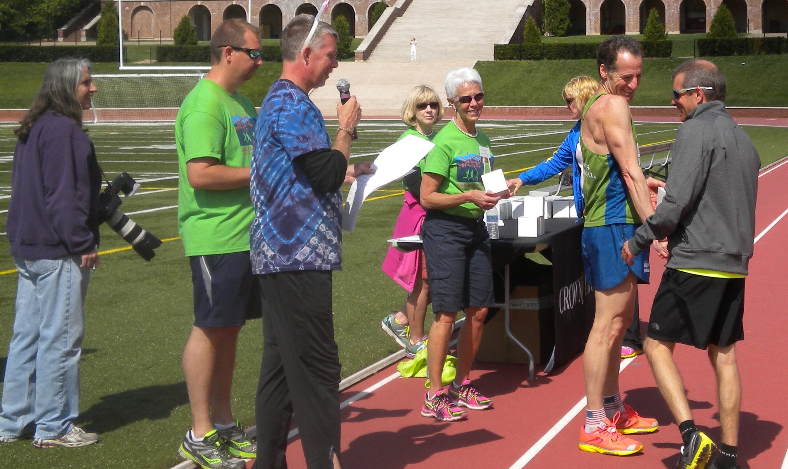 Doug Landau shakes AG winner John Curcio's hand during the awards ceremony after the Winchester Virginia Shenandoah Apple Blossom Festival 10 km. road race Doug Landau shakes AG winner John Curcio's hand during the awards ceremony after the Winchester Virginia Shenandoah Apple Blossom Festival 10 km. road race