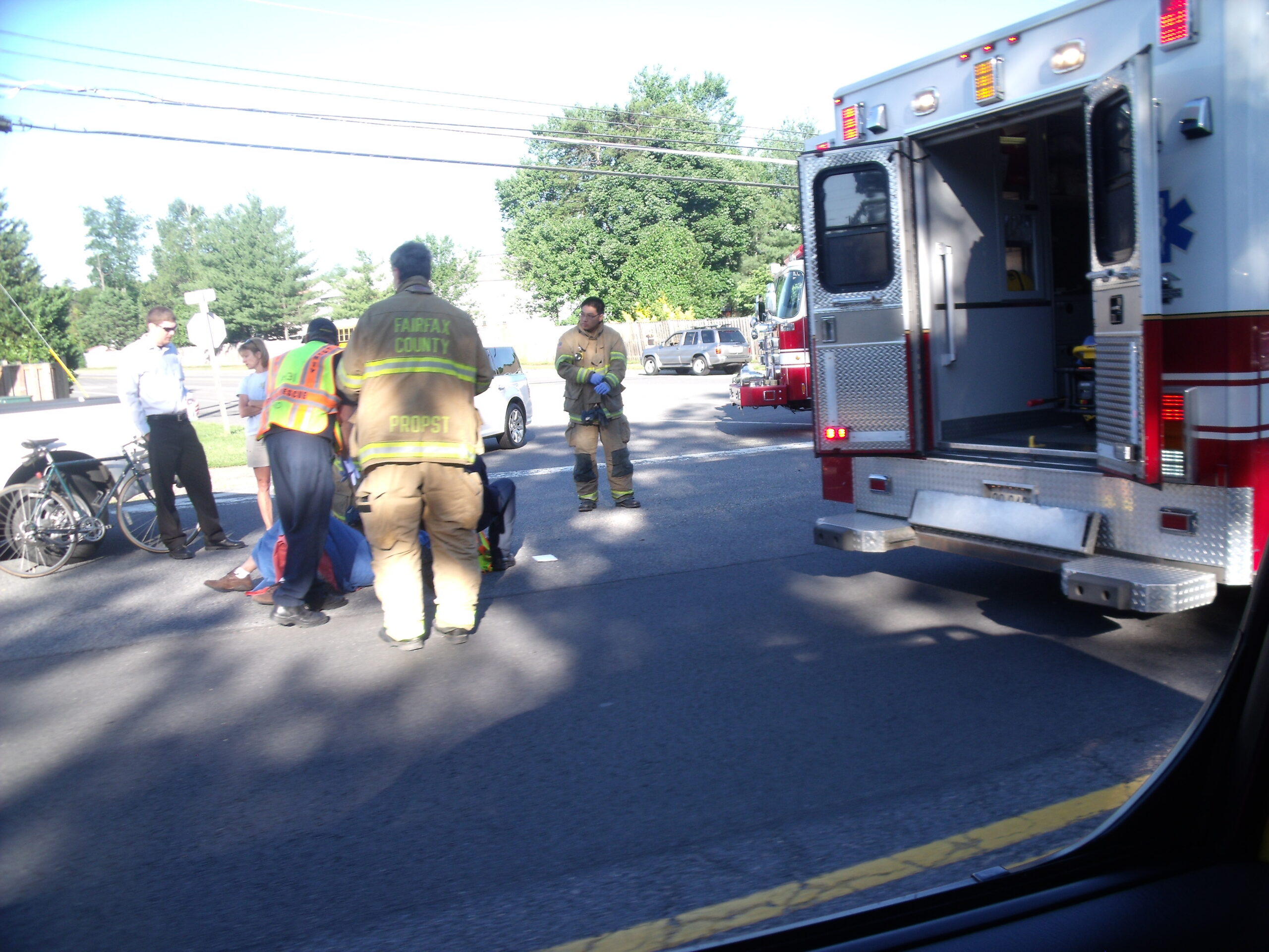 EMTs assess, secure and prepare to transport thte injured biker this morning after an apparent crash at West Ox Road and Ashburton, in Oak Hill, Virginia